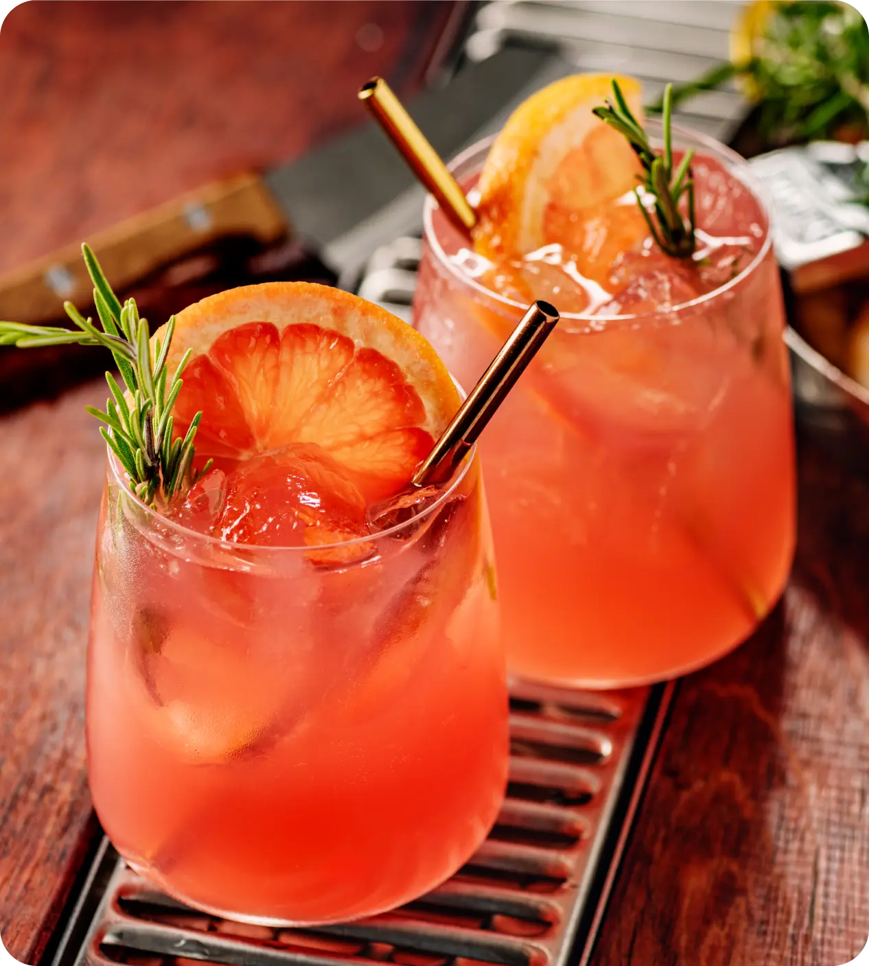 Two refreshing pink cocktails garnished with citrus and mint.