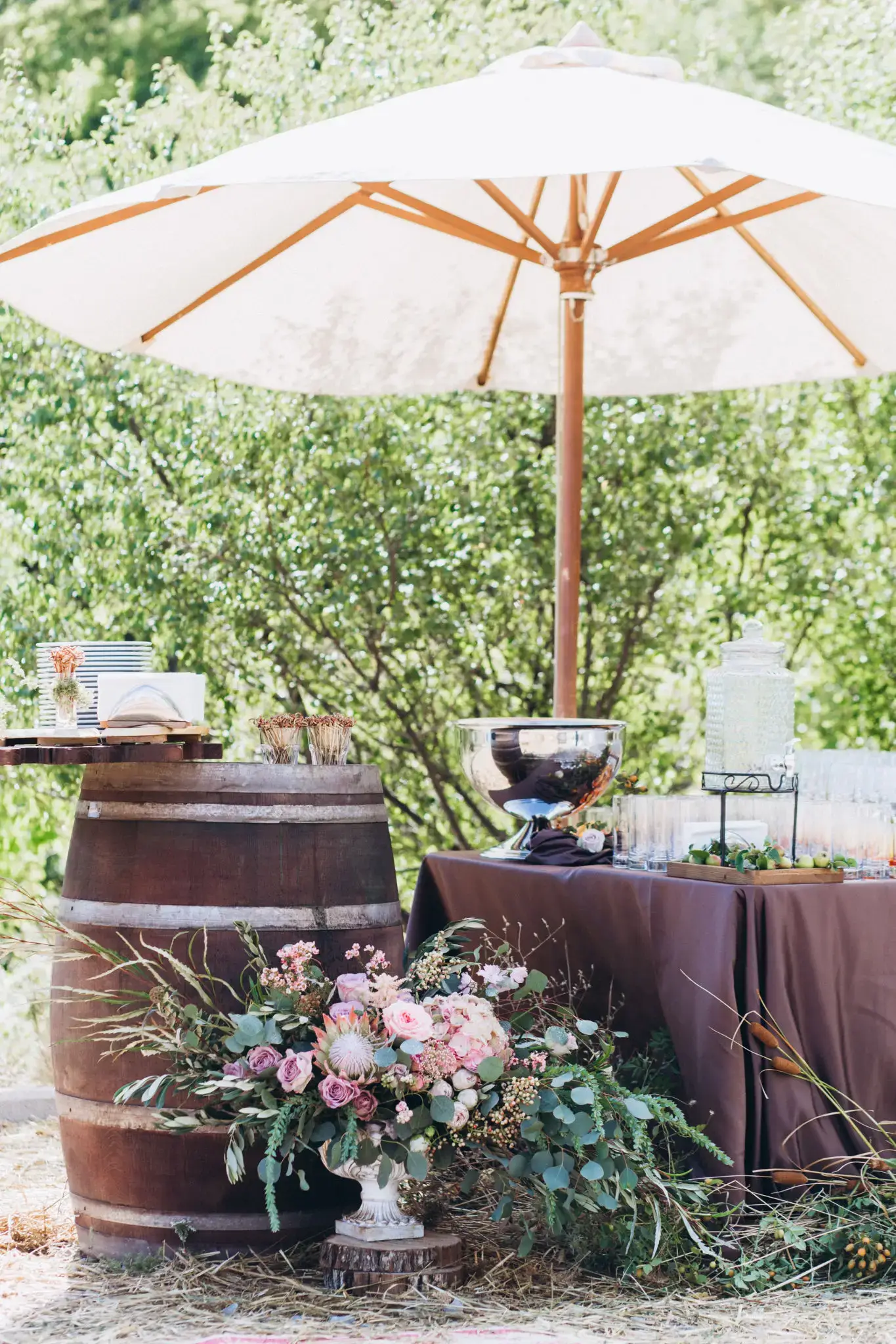 Elegant outdoor wedding setup with floral decor and a large umbrella.