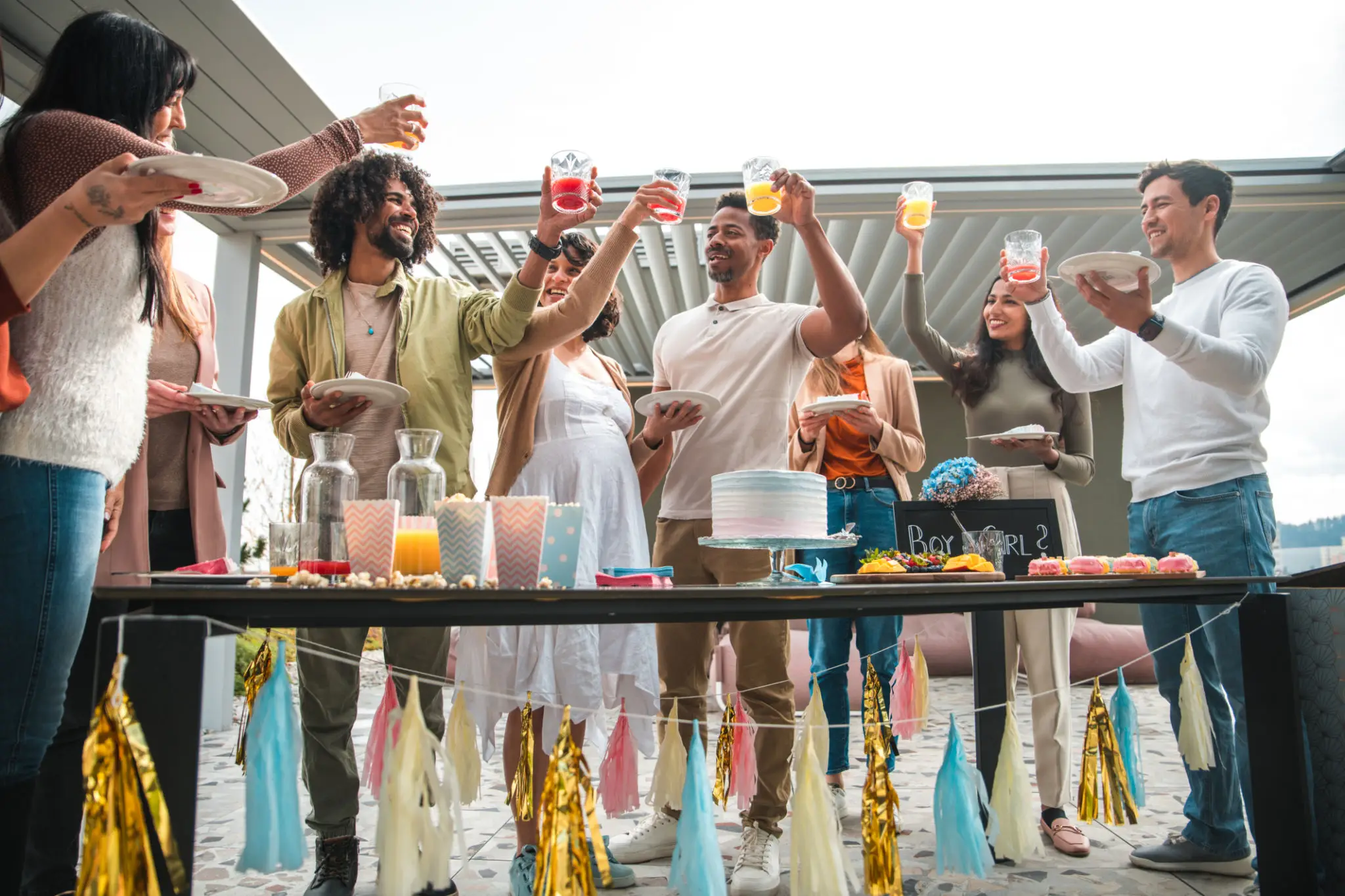 Group of people joyfully cheering with drinks outdoors.