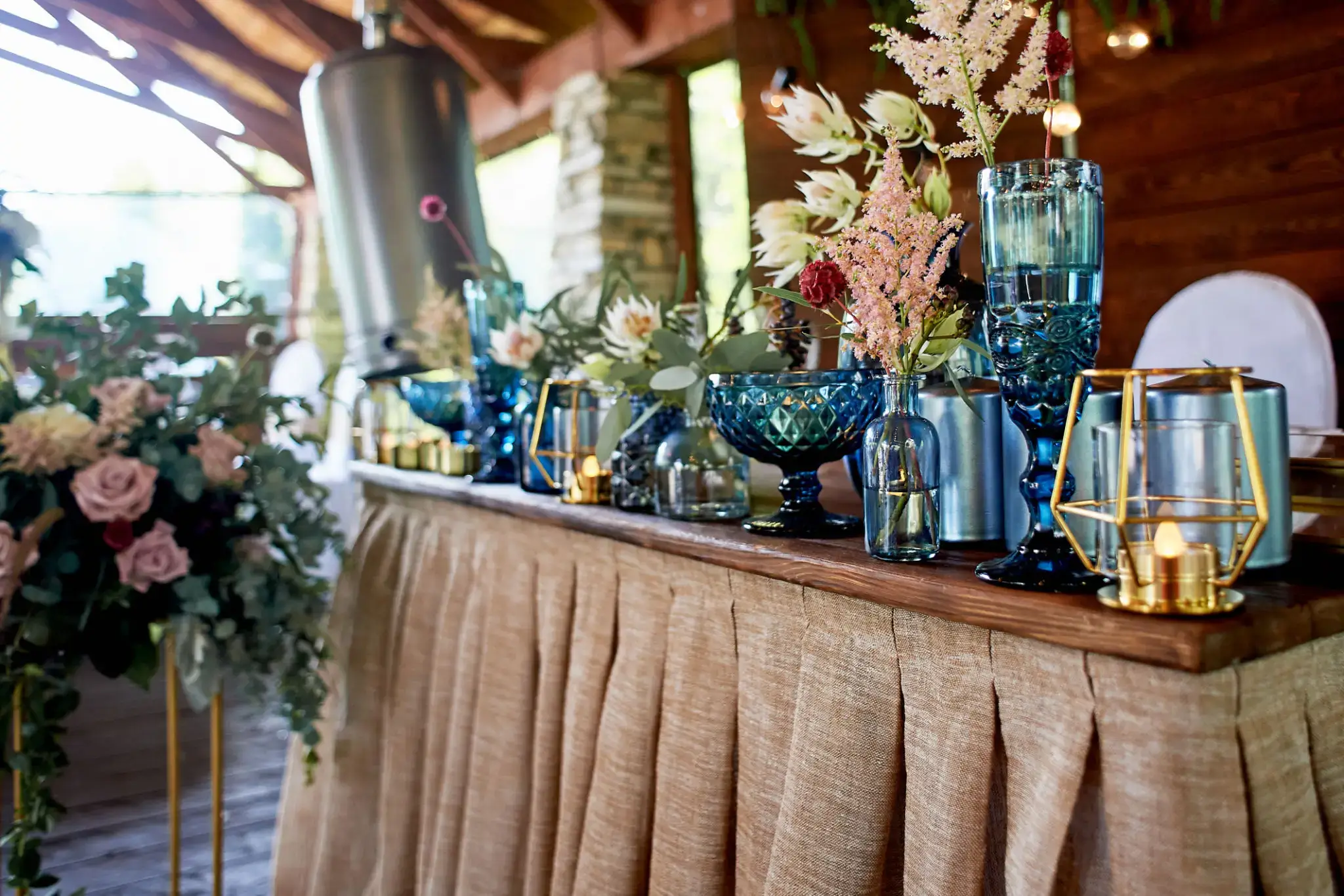 Elegant table setup with blue glassware and dried floral arrangements.